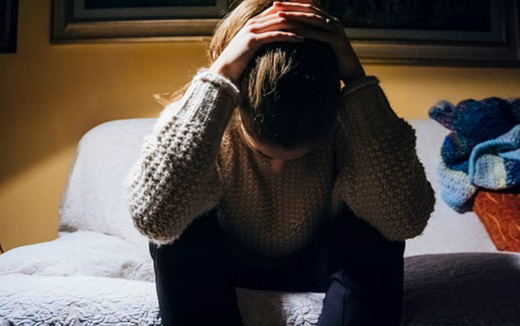 Girl who looks stressed holding her hair back and looking downwards